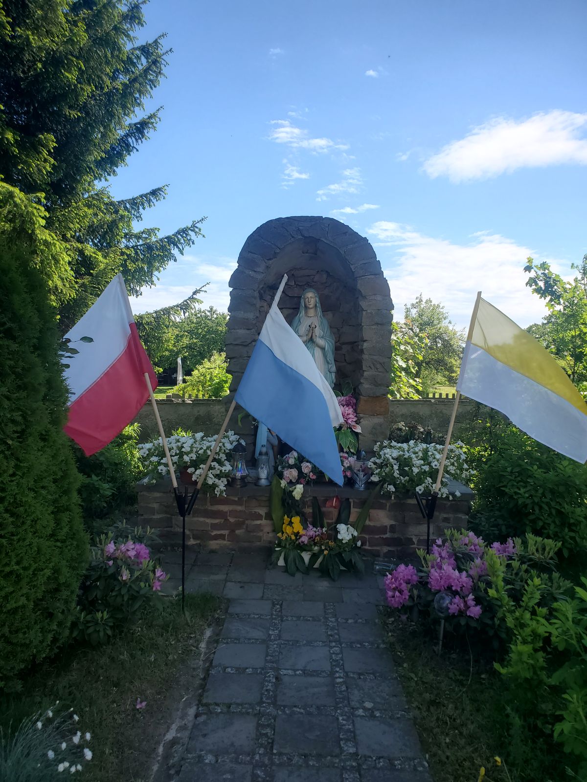 Altar in catholic church yard containing national flags and, but not 100% sure, Mary Magdalene statue